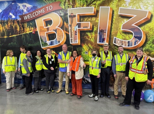 A group of people in reflective vests in front of a sign that says "Welcome to BF13".