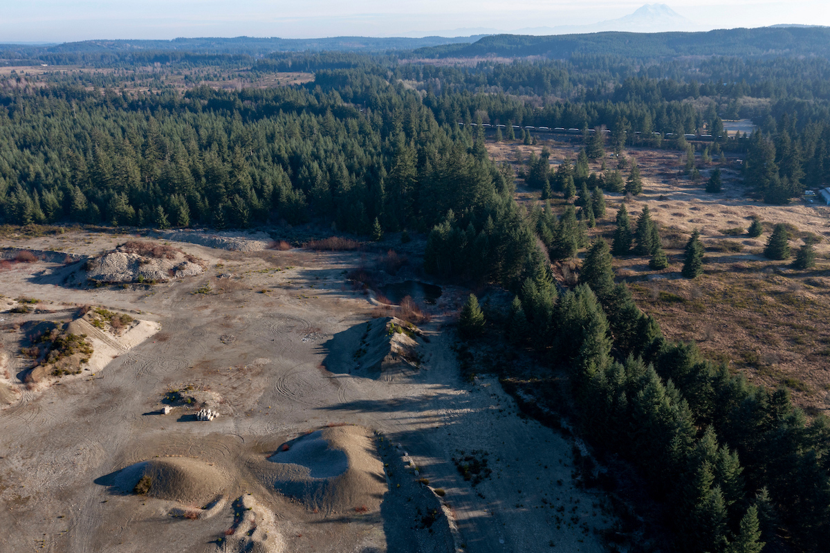 Trees surrounding a gravel mine yard.