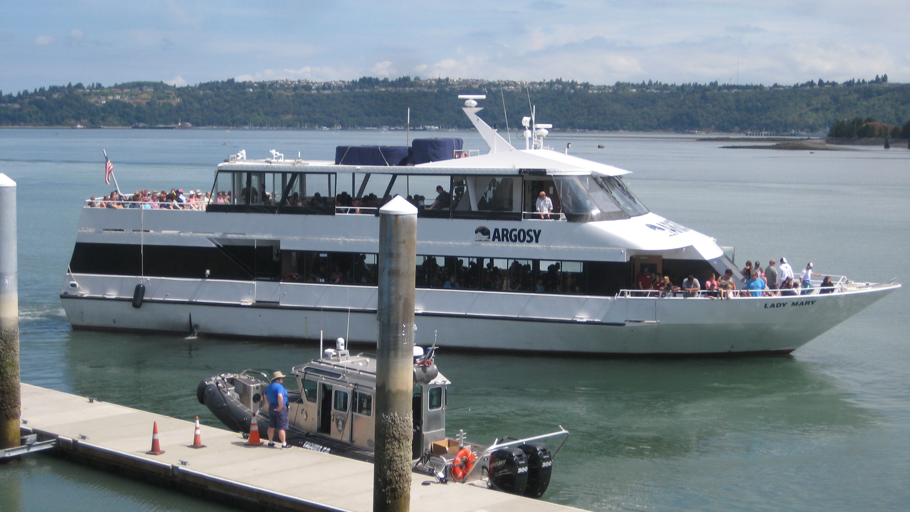A large Argosy cruise ship pulls into a dock on a sunny day. 